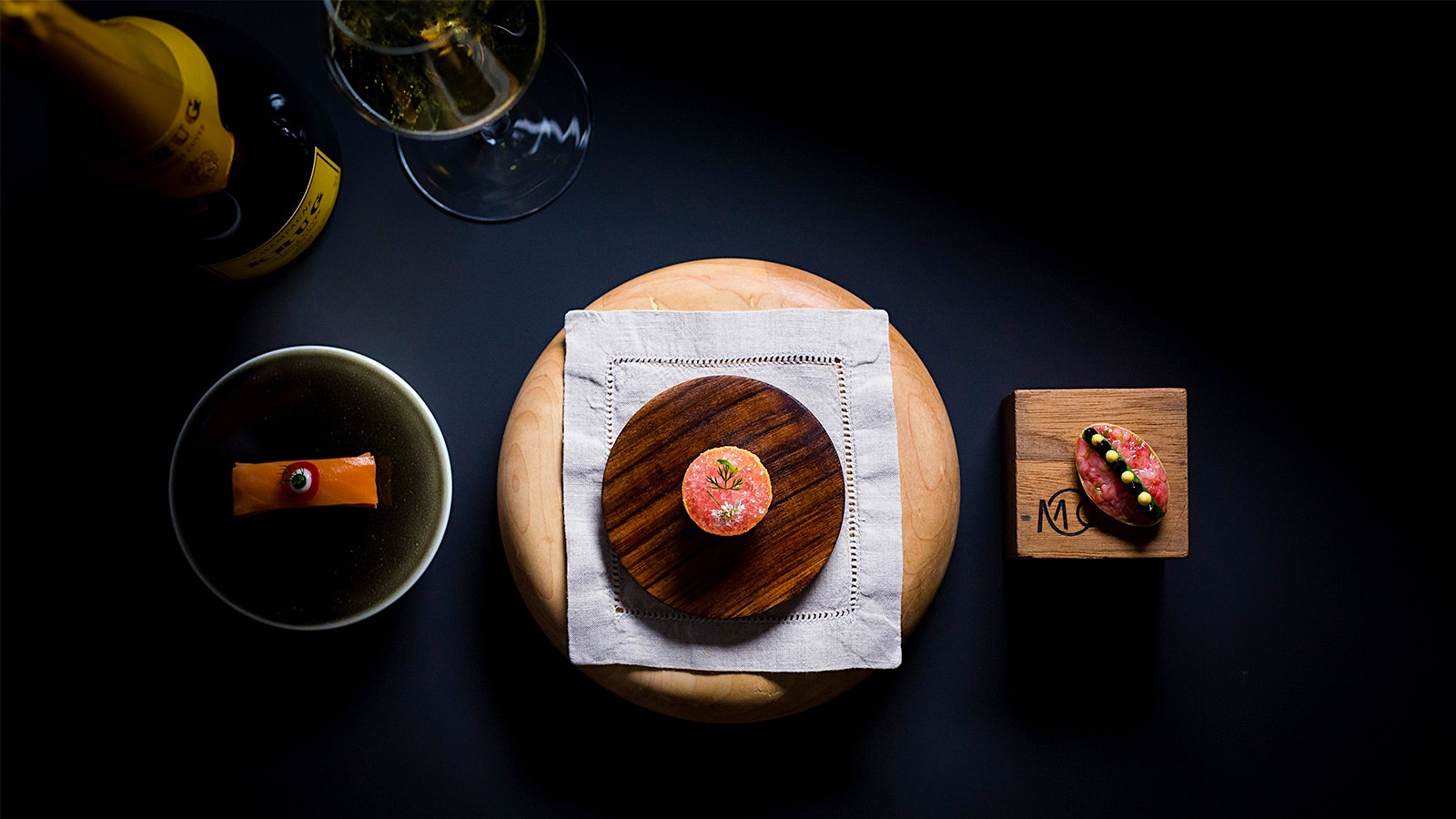 A bottle of wine and a selection of seafood dishes from Providence chef Michael Cimarusti